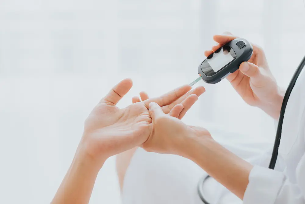 イメージ画像:患者の手から血糖値測っている医者